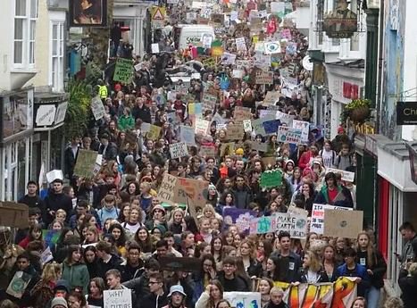 Large group of young people marching in street with signs